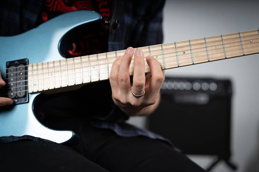 exercice-guitare-manche-accords une main sur un manche de guitare électrique qui fait des accords