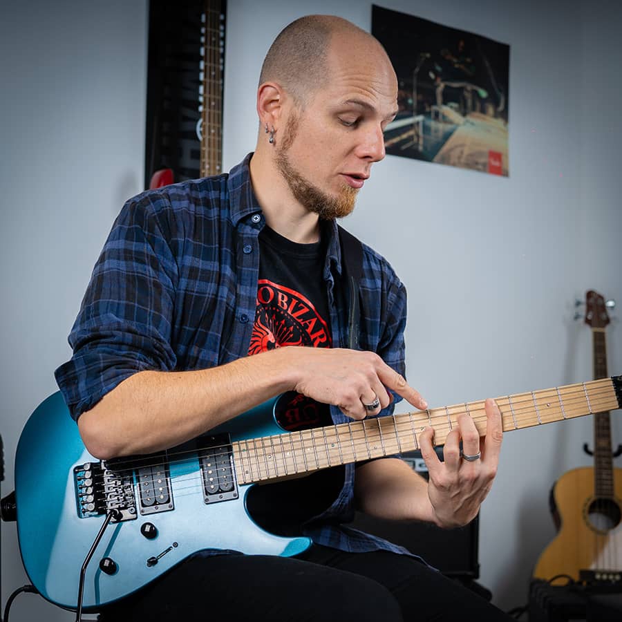 exercice-guitatre-electrique un professeur montre comment tenir ses doigts sur un manche de guitare