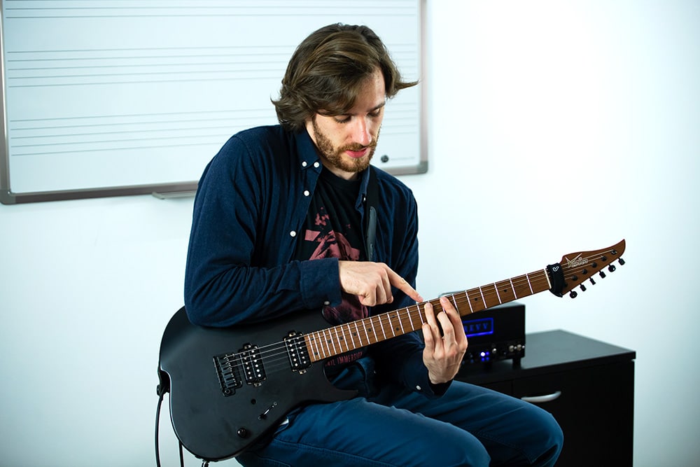 photo-professeur-guitare photographie du professeur de guitare indiquant où placer ses doigts sur le manche