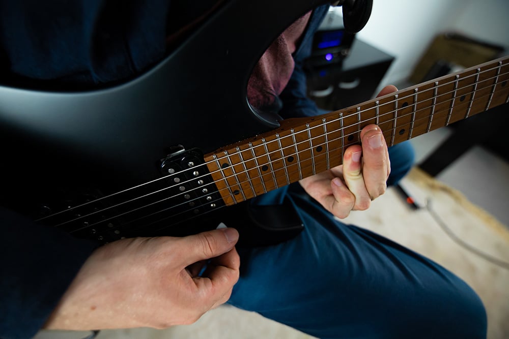 une main sur un manche de guitare électrique qui fait des accords