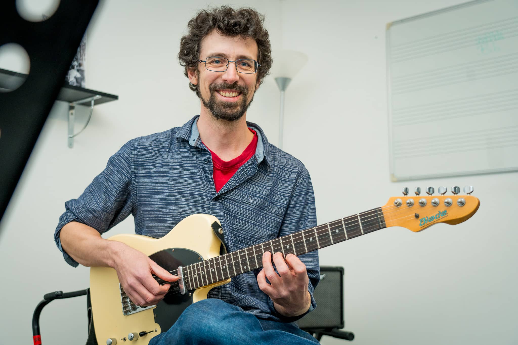 un professeur montre comment tenir ses doigts sur un manche de guitare